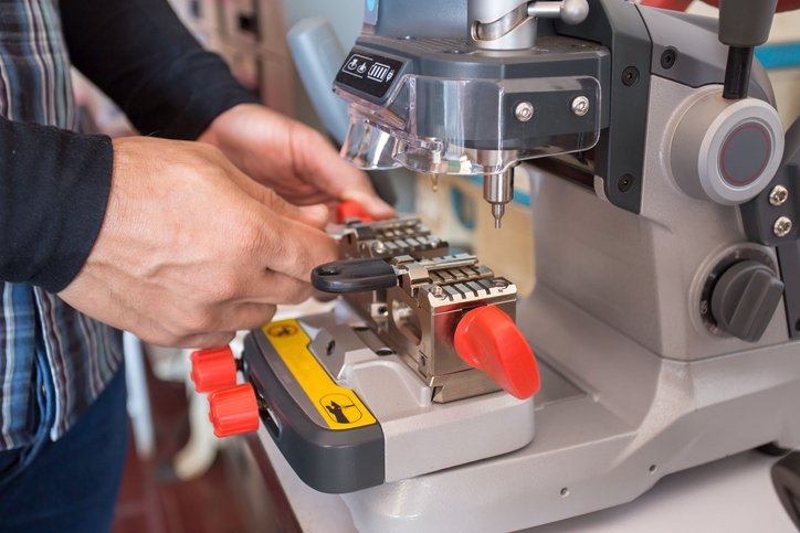 Locksmith in workshop makes new key. Professional making key in locksmith.